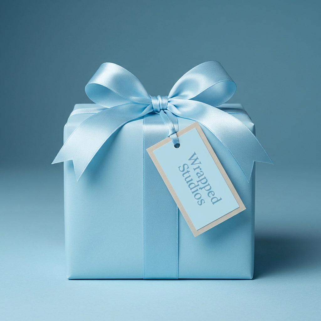 Elegant light blue gift wrap on a square present with a satin ribbon and a tag.