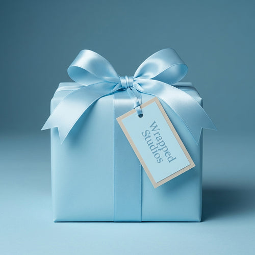 Elegant light blue gift wrap on a square present with a satin ribbon and a tag.