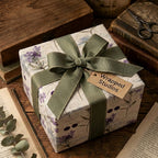 Square gift wrapped in purple floral paper, olive grosgrain ribbon, from Wrapped Studios.