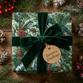 Luxury Christmas wrapping paper with pine pattern and green velvet ribbon by Wrapped Studios.