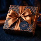 Luxury navy and bronze damask wrapping paper on a gift box with satin bow by Wrapped Studios.
