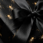 Elegant black gift wrap with a beetle pattern tied with a satin ribbon bow.