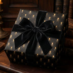 Elegant gift wrapped in beetle-patterned wrapping paper with a luxurious black velvet bow.