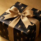 Elegant gift box wrapped in black beetle print wrapping paper with a gold ribbon bow.
