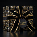 Elegant Christmas gift wrapped in black & gold ornament pattern paper, tied with a velvet ribbon bow.