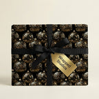 Elegant black and gold Christmas wrapping paper with ornament pattern and ribbon.
