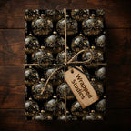 Elegant black and gold Christmas wrapping paper featuring ornament pattern and twine bow.