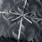 Elegant gift wrapped in dark grey wrapping paper with a modern floral pattern and silver ribbon.