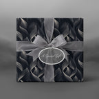 Elegant gift box wrapped in dark gray floral wrapping paper with sheer silver ribbon and "A Special Gift" tag.