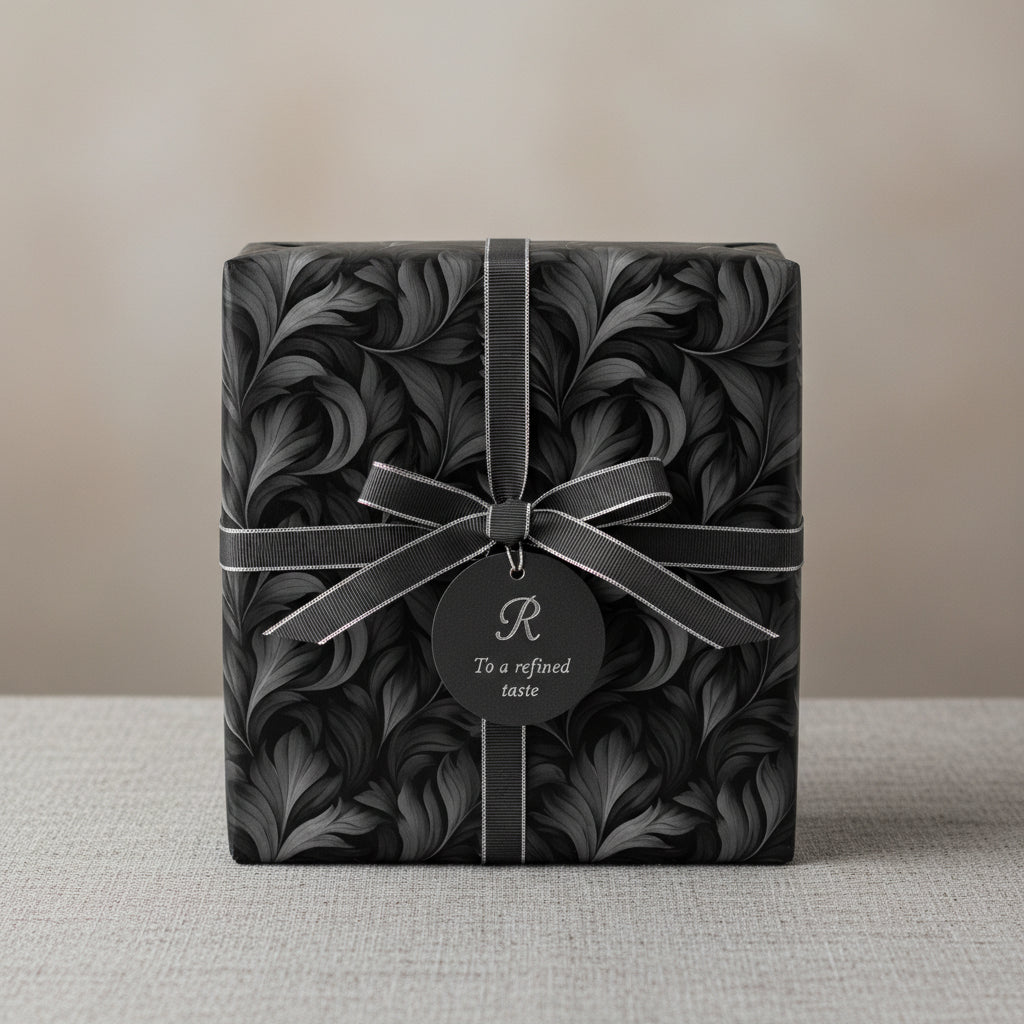 Elegant gift box wrapped in luxury black floral wrapping paper with silver ribbon and tag.