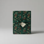 Elegant Christmas gift wrapped in dark green floral wrapping paper with red berries and tied with satin ribbon.