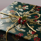Elegant Christmas gift wrap with gold ribbon, berries, and dark green floral pattern.