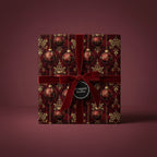 Elegant Christmas gift wrapped in red and gold ornament-patterned wrapping paper with a velvet ribbon.