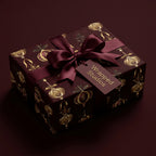 Elegant holiday gift beautifully wrapped in burgundy paper with gold ornament design from Wrapped Studios.