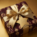 Elegant burgundy Christmas wrapping paper with gold ribbon, bow, and "Joy" tag.