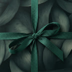 Elegant gift wrapped in abstract dark green floral wrapping paper with satin ribbon.