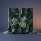 Elegant dark green gift wrapped with botanical pattern paper and sheer ribbon bow.