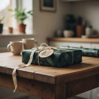 Gift wrapped in green botanical wrapping paper with ribbon and a tag.