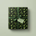 Green floral wrapping paper on a square gift box with satin ribbon and a tag.