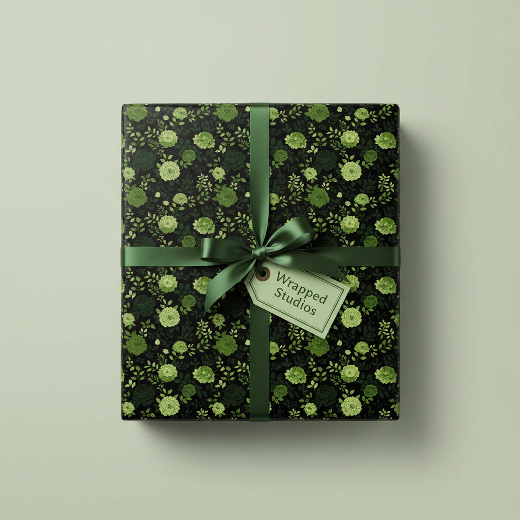 Green floral wrapping paper on a square gift box with satin ribbon and a tag.