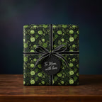 Dark floral wrapping paper with black ribbon and "To Mom, with love" tag.