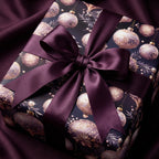 Elegant Christmas gift wrapped in purple ornament patterned paper with satin bow.