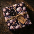 Elegant Christmas gift wrap with ornate ornament pattern, tied with rustic twine and "Cheers" tag.