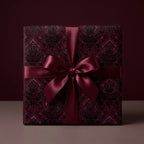 Burgundy gift box wrapped in luxury damask wrapping paper with a satin ribbon bow.