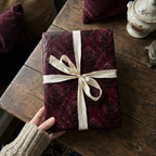 Burgundy gift wrapped in damask wrapping paper with cream ribbon, perfect for luxury birthday or holiday gift wrap.