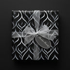Elegant gift wrap with black and silver abstract design, tied with sheer ribbon and "Timeless Beauty" tag.