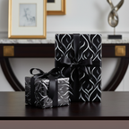 Two gifts wrapped in black and silver modern wrapping paper with elegant black ribbon bows.