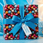 Macaron themed wrapping paper on a gift box tied with a bright blue ribbon.
