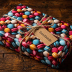 Colorful macaron print wrapping paper with twine and handmade tag for a sweet gift.