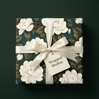 Luxury dark green floral wrapping paper with white roses and a cream satin bow by Wrapped Studios.
