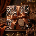 Elegant brown marble swirl luxury wrapping paper with bronze satin bow by Wrapped Studios.