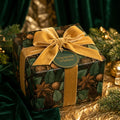 Luxury Christmas gift wrap with botanical pinecone print and gold velvet ribbon by Wrapped Studios.