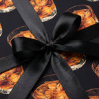 Whiskey glass pattern gift wrap with black ribbon for unique birthday wrapping paper.