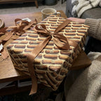 Gift wrapped in cigar print wrapping paper with bronze ribbon on a wooden table.