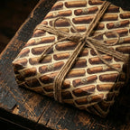 Cigar print wrapping paper on a gift box, tied with rustic twine, on a wooden surface.