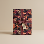 Rectangular gift wrapped in modern camouflage-style paper with a burgundy ribbon.
