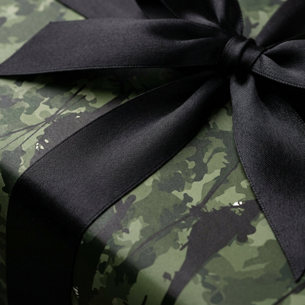 Green camo wrapping paper with a black satin bow on a gift box by Wrapped Studios.