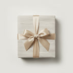 Elegant gift box wrapped in minimalist light gray woodgrain paper with a gold satin ribbon.