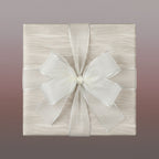 Elegant gift wrapped in beige woodgrain paper with sheer white ribbon and silver trim.