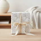 Elegant modern floral wrapping paper with delicate black leaf outlines and a cream ribbon, perfect for minimalist gift presentation.