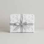 Modern white floral wrapping paper with delicate black leaf outlines and a sophisticated gray ribbon bow, perfect for elegant gifts.