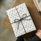 Minimalist black cross wrapping paper with twine bow for baptism or Easter gifts by Wrapped Studios.