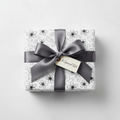 Elegant white wrapping paper with a black floral and scroll pattern, tied with a dark gray satin ribbon and a "A Special Gift" tag.