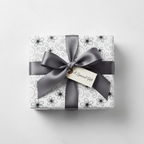 Elegant white wrapping paper with a black floral and scroll pattern, tied with a dark gray satin ribbon and a "A Special Gift" tag.