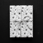 Elegant white floral wrapping paper with black hand-drawn flowers and silver ribbon, perfect for luxury birthday or wedding gifts.