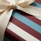 Luxury striped wrapping paper in burgundy and blue with a cream satin bow, by Wrapped Studios.